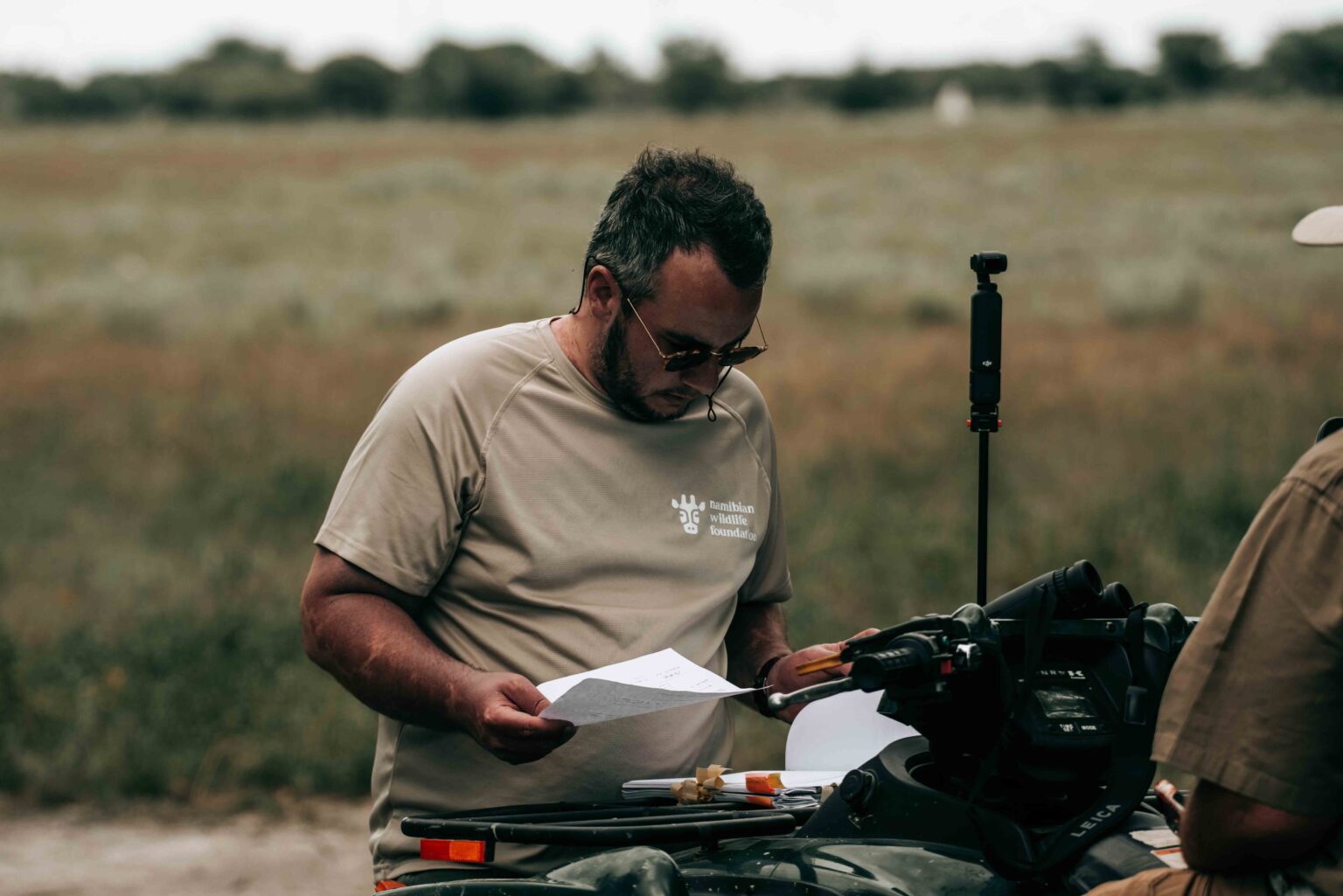 Teammitglied der Namibian Wildlife Foundation mit Unterlagen im Gelände als Symbolbild für Wissen, Austausch und Naturschutzarbeit