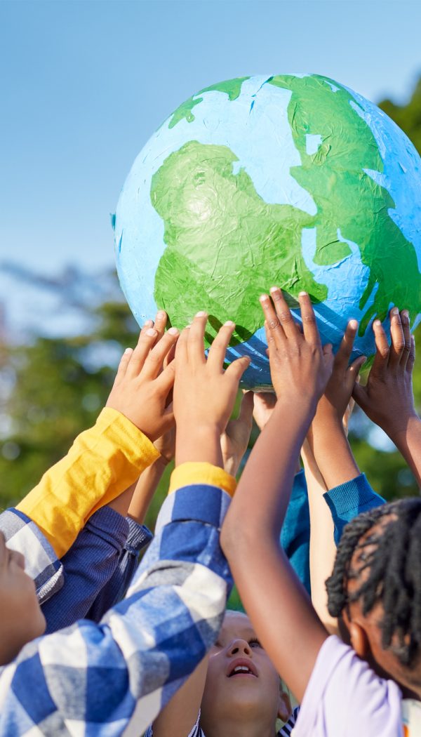 Kinder stehen im Kreis und halten gemeinsam einen Globus in die Höhe.